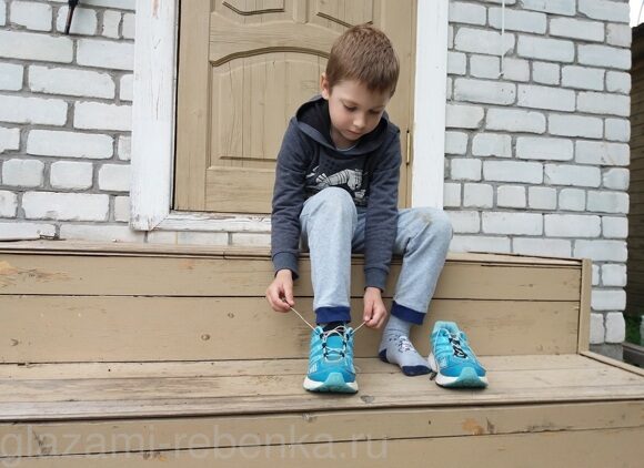 Мальчик завязывает шнурки